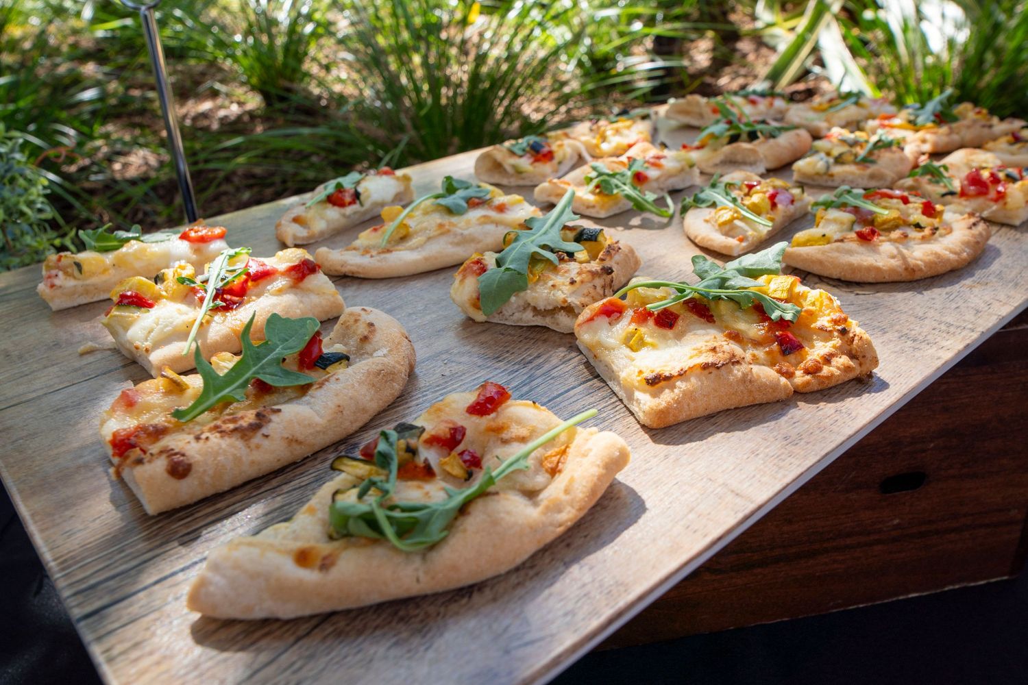 Artisanal flatbread appetizers with fresh toppings displayed on wooden serving boards.