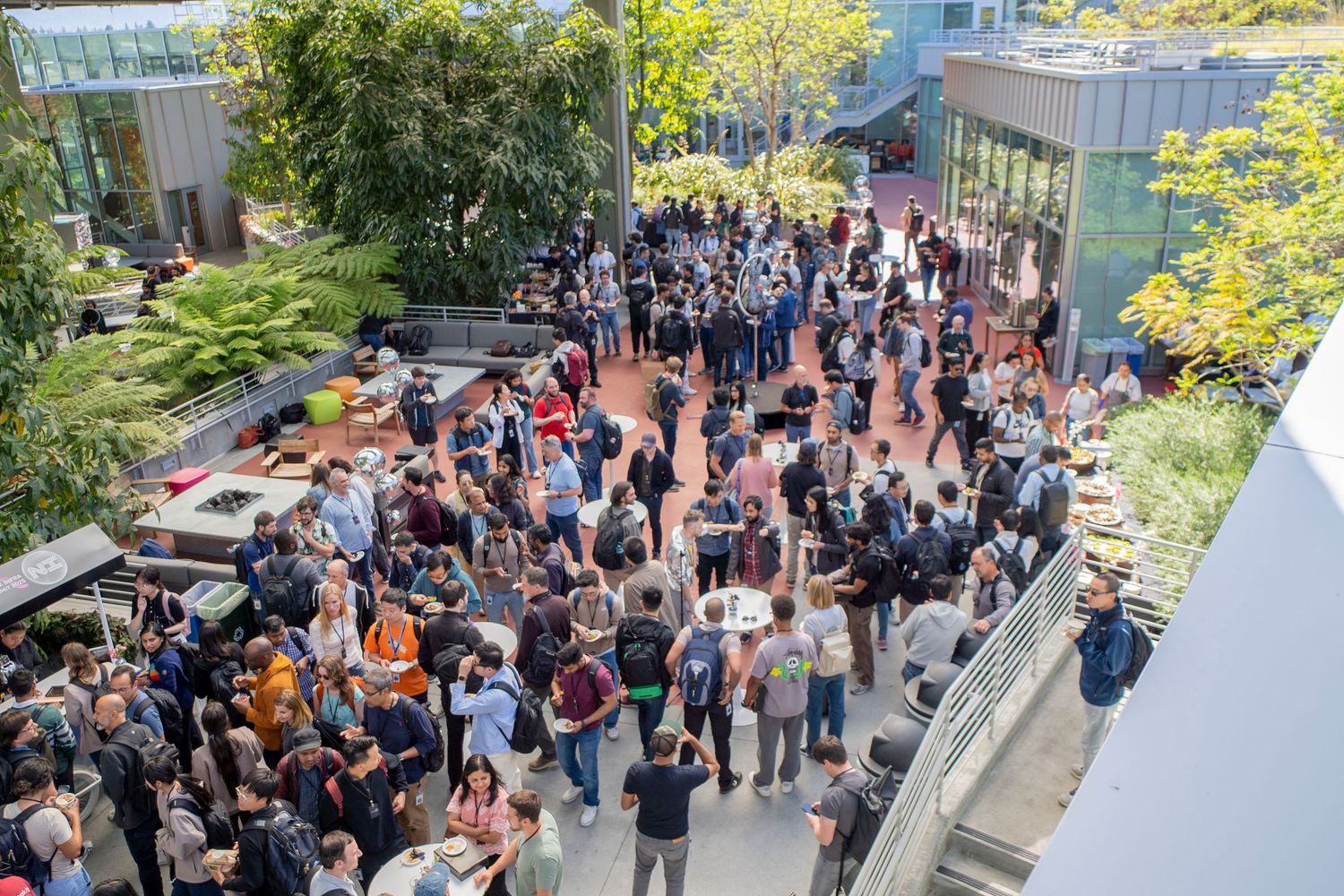 Large crowd gathered in an outdoor courtyard surrounded by modern architecture.