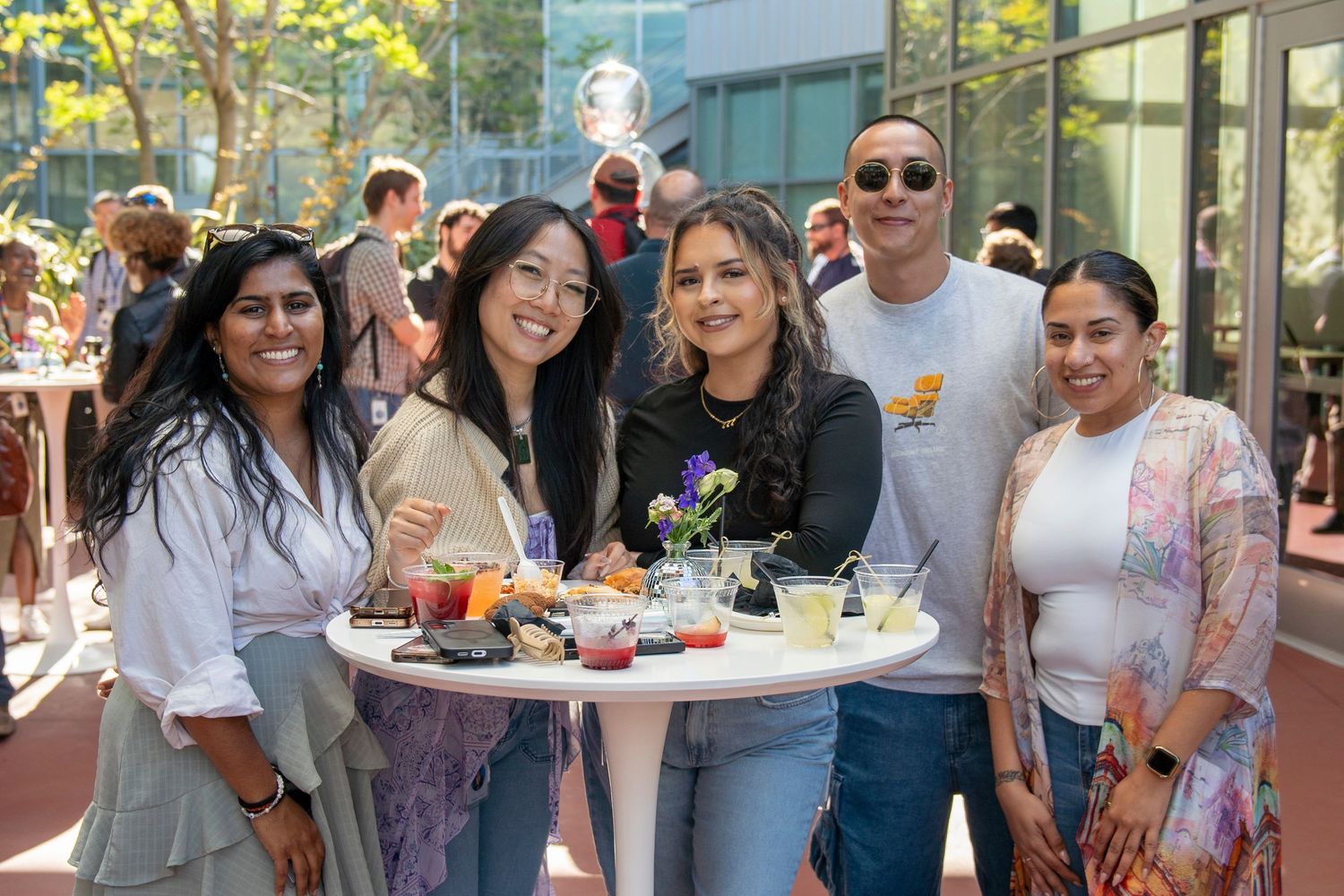 Group enjoying refreshments at an outdoor gathering with modern building backdrop.