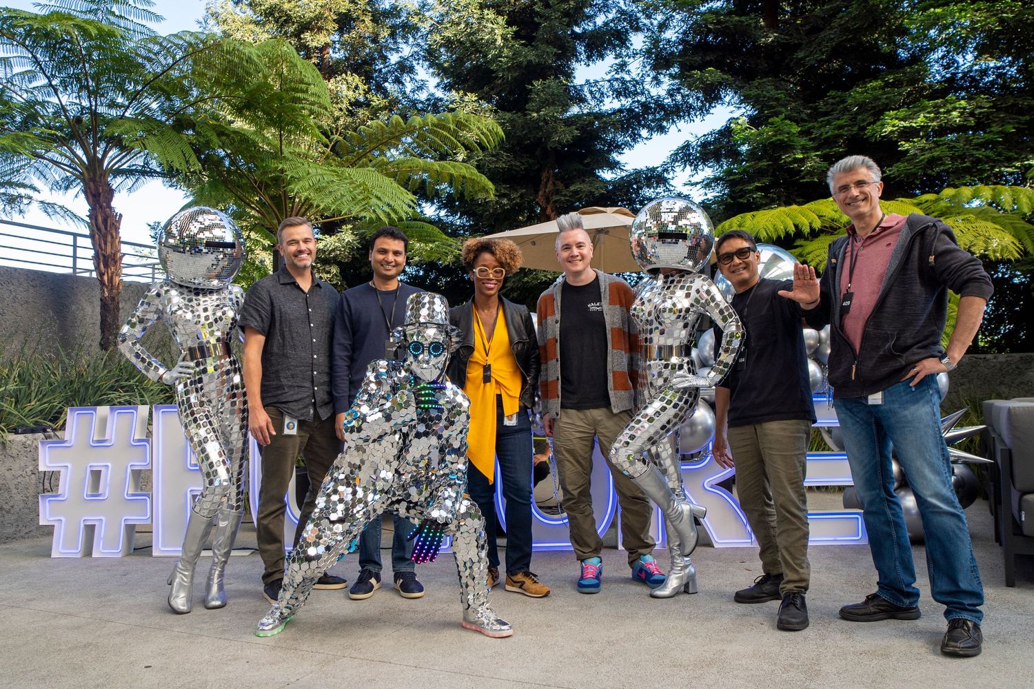 Outdoor installation with silver sculptures and white text display among trees.