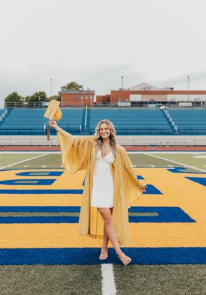 senior girl blue and gold white dress gold cap and gown football field