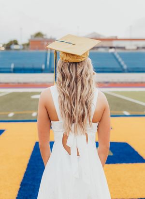 senior girl blue and gold white dress gold cap and gown football field