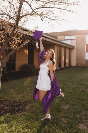 Graduate senior girl white dress purple cap and tassel and gown golden hour