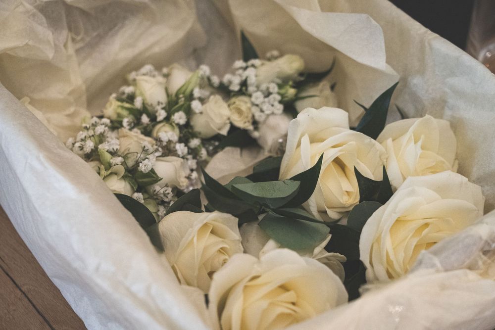 Close-up view of delicate cream roses and white baby's breath arranged with sheer fabric at a wedding celebration.