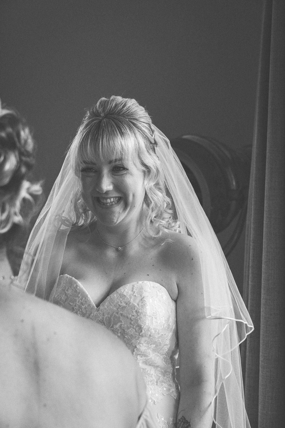 Black and white bridal portraits show joyful moments while wearing a strapless lace wedding gown and flowing veil.