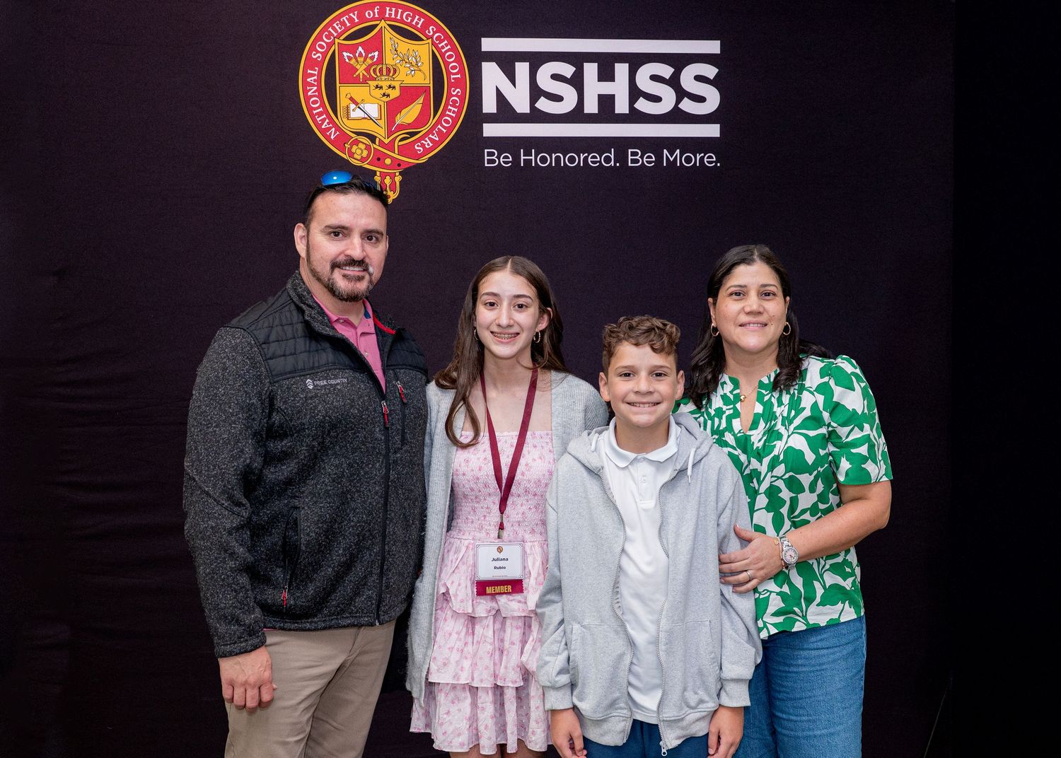 Group photo taken at NSHSS event with promotional backdrop.