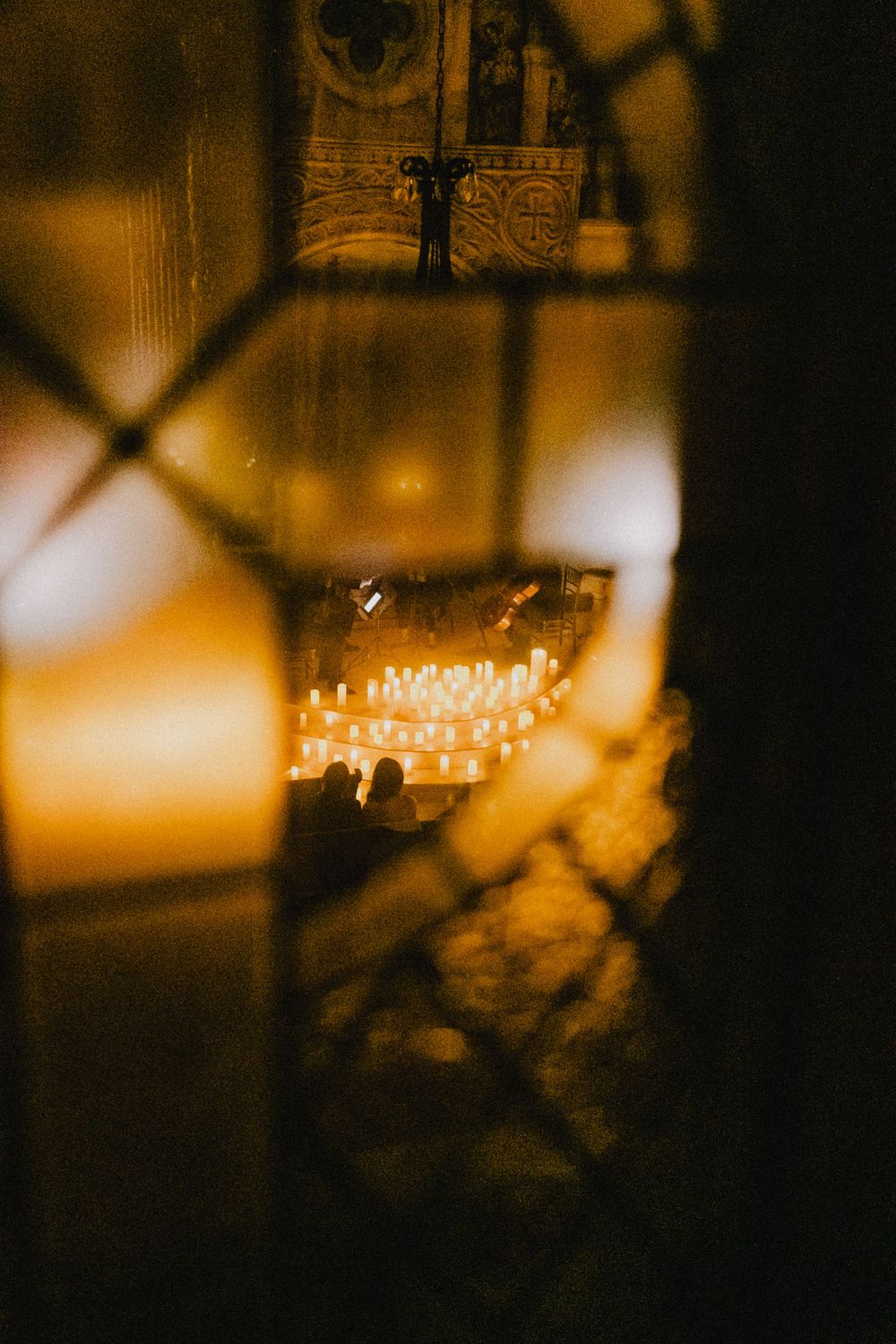 Romantic candlelit church interior viewed through an ornate iron gate with warm golden light glowing.