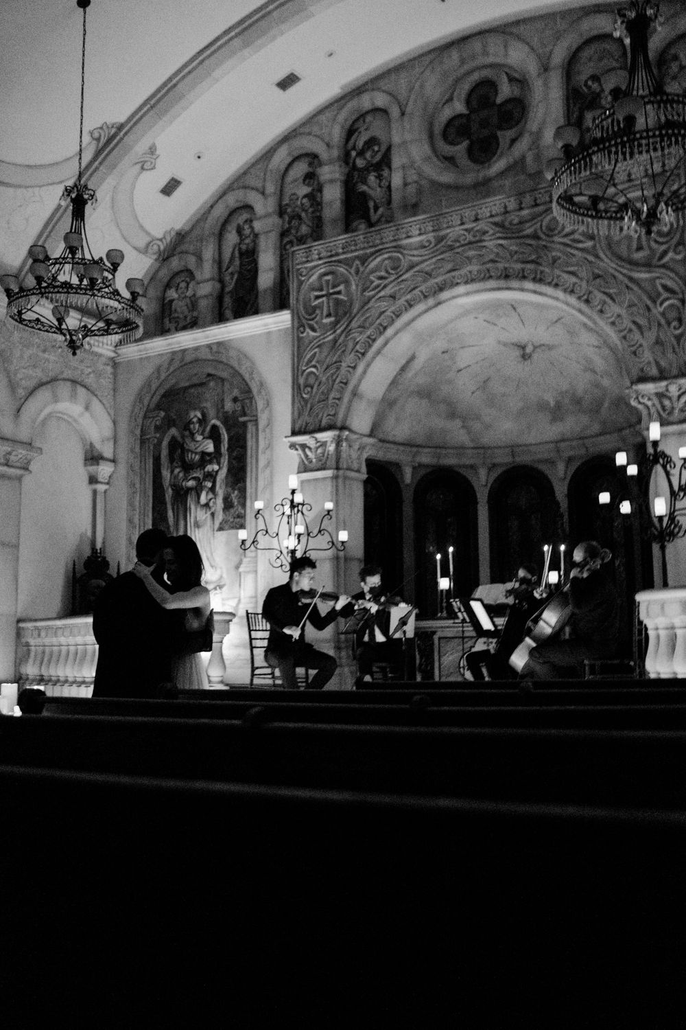 Black and white photo of a string quartet performing in an ornate church with Byzantine-style frescoes.
