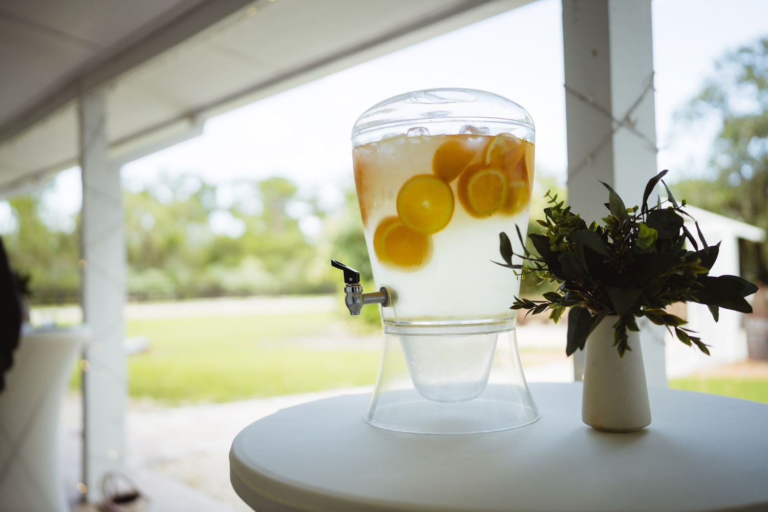 A series of cocktail glasses on a white surface feature fresh citrus garnishes and white decorative flowers.