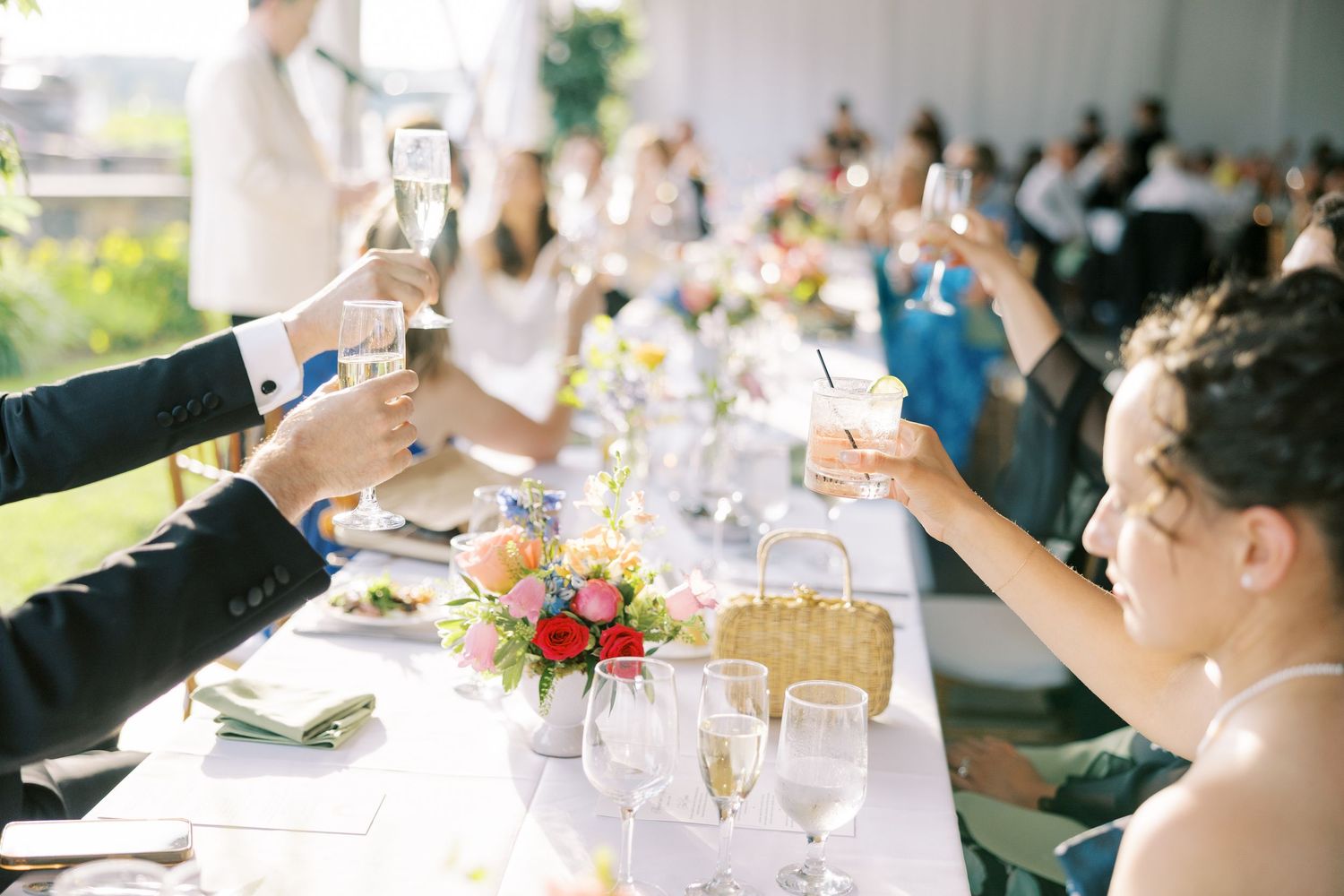 Wedding guests raising champagne glasses in a toast during an elegant reception dinner celebration.
