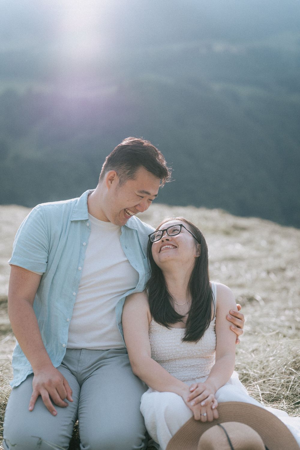 Happy couple sitting and laughing together on a mountain overlook.