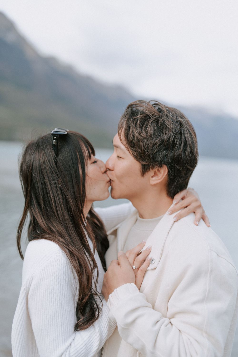 Romantic couple sharing an intimate kiss against a mountainous backdrop.