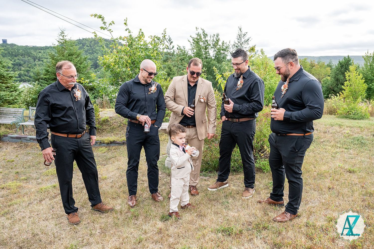 Group of wedding guests interacting on a grassy slope during an outdoor celebration.