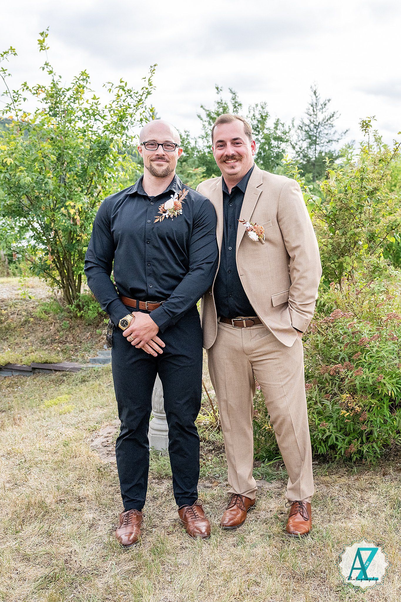 Two men in contrasting black and tan suits pose outdoors showing off their boots in a casual fashion shoot sequence.