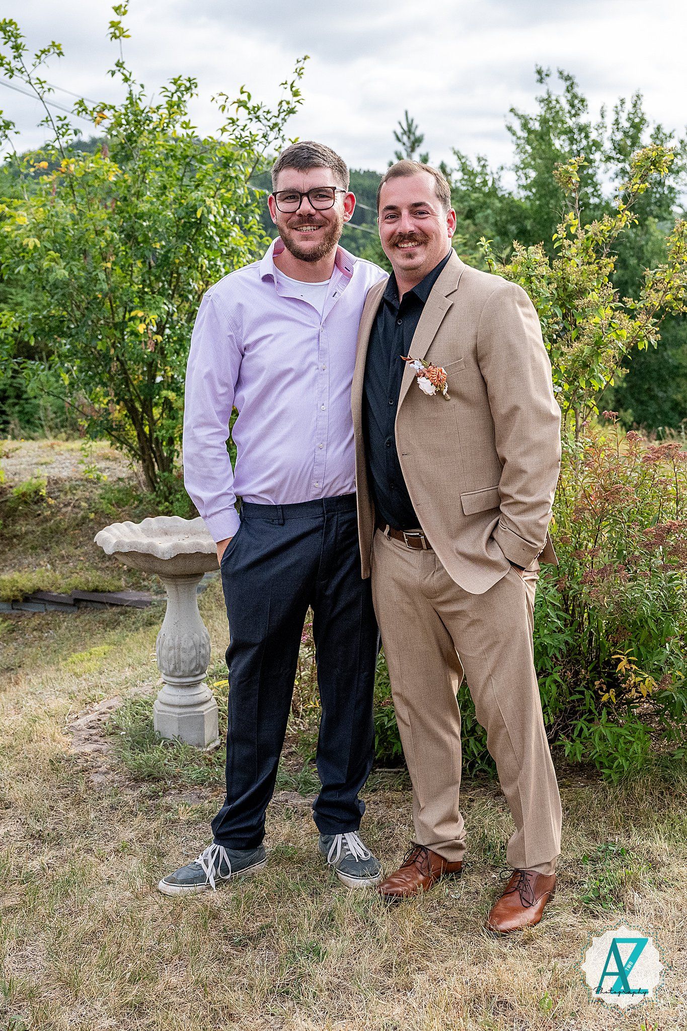 Joyful interactions between wedding attendees on a grassy slope with bushes in the background.