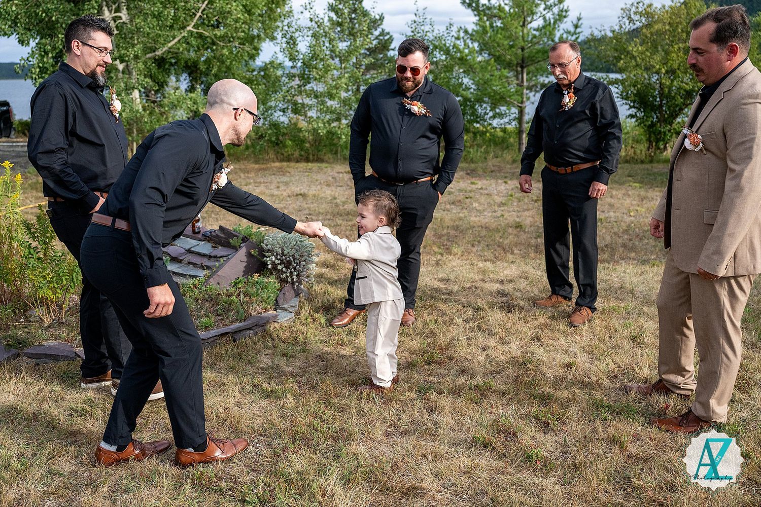 Guests gathering on a hillside during an outdoor celebration with greenery in the background.
