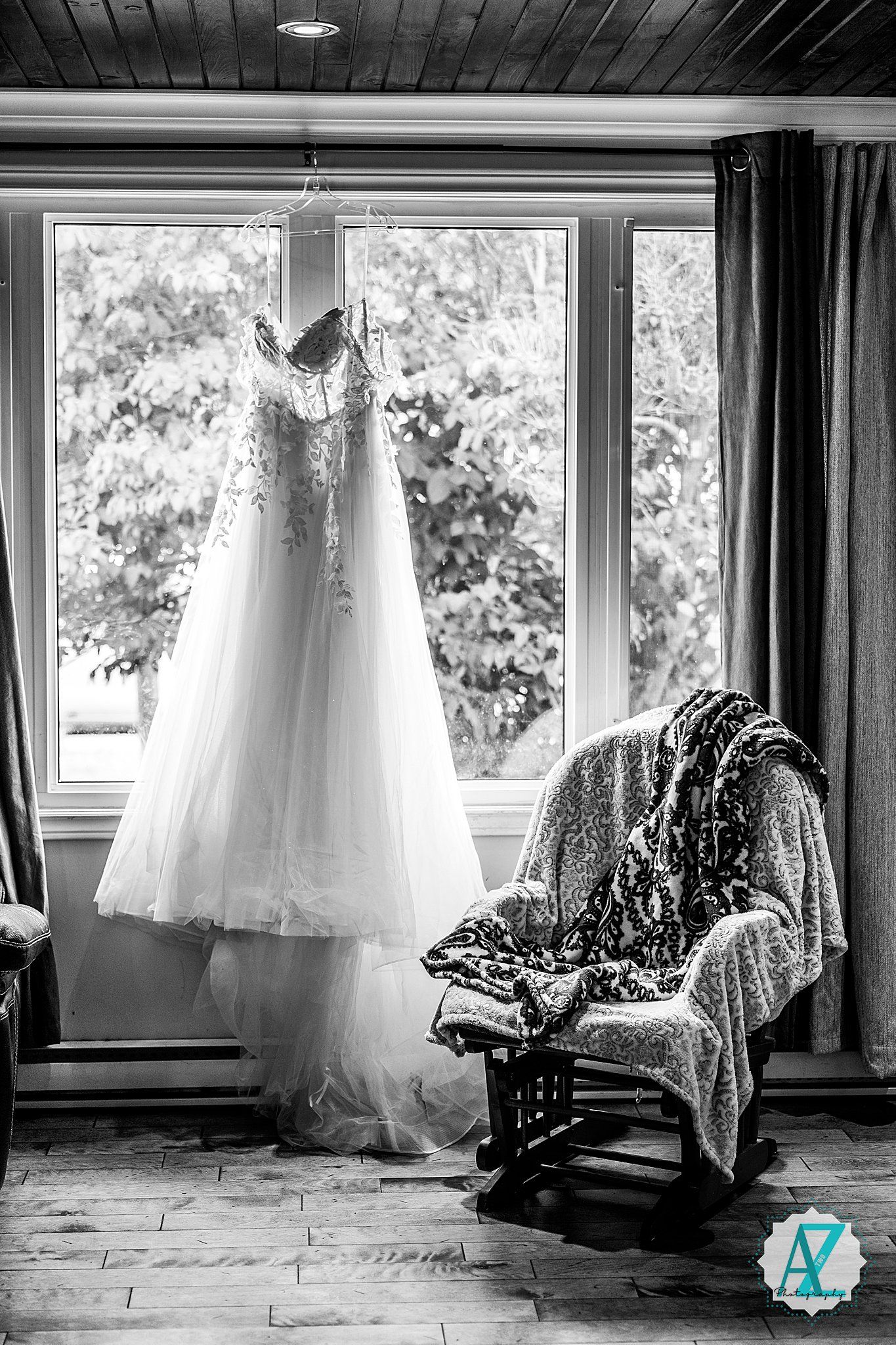 Four cinematic black and white photos show a wedding dress hanging in a window beside a vintage armchair.