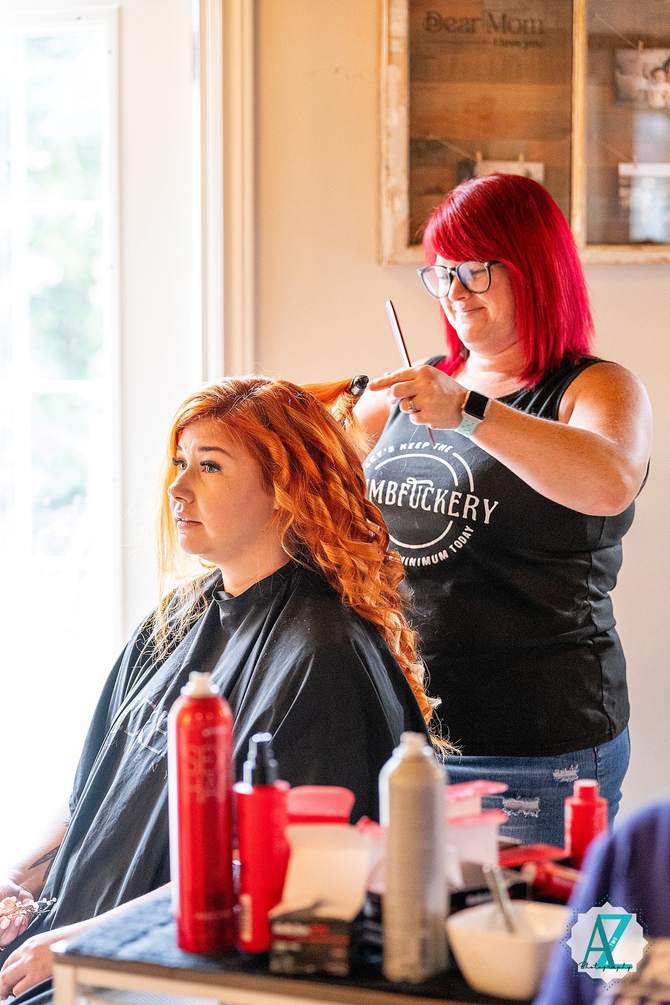 Wedding preparation scene with hairstyling taking place in a bright room with beauty products visible.