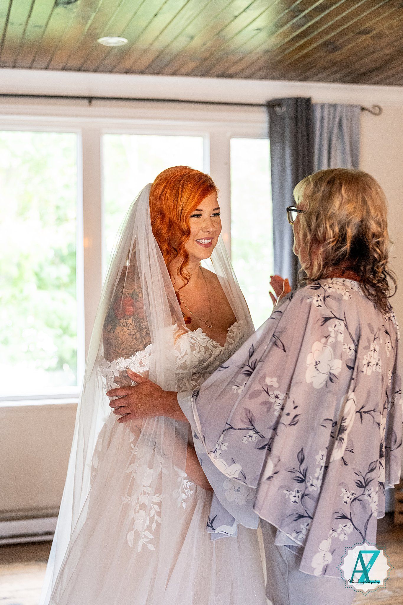 Bridesmaids in floral robes help prepare the bride in her elegant white wedding dress.