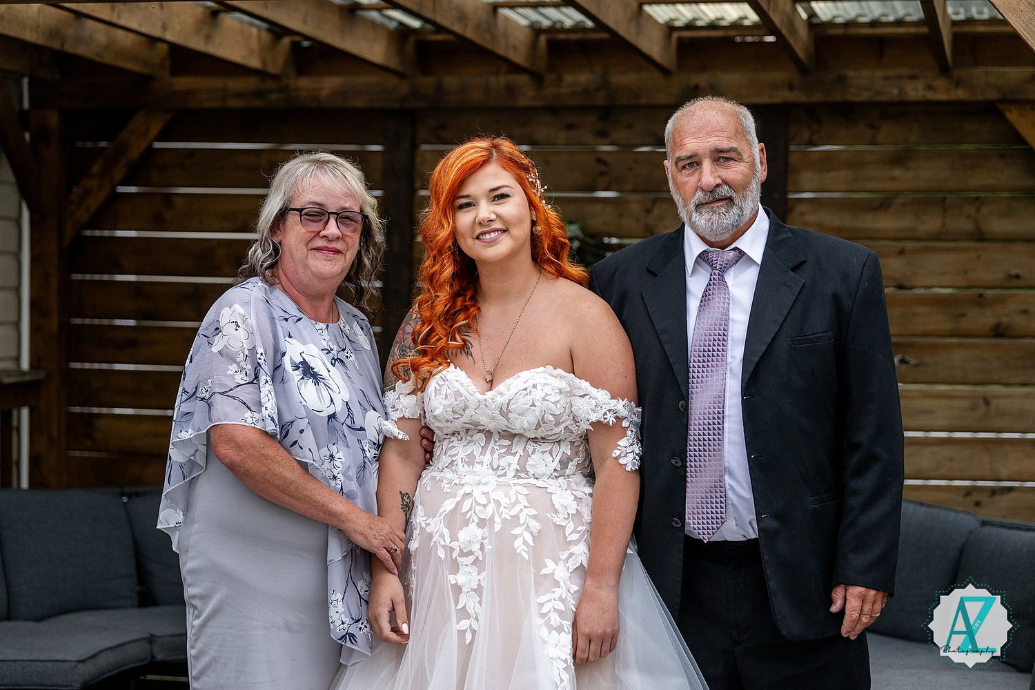 Wedding party poses on rustic wooden porch with barn-style backdrop.