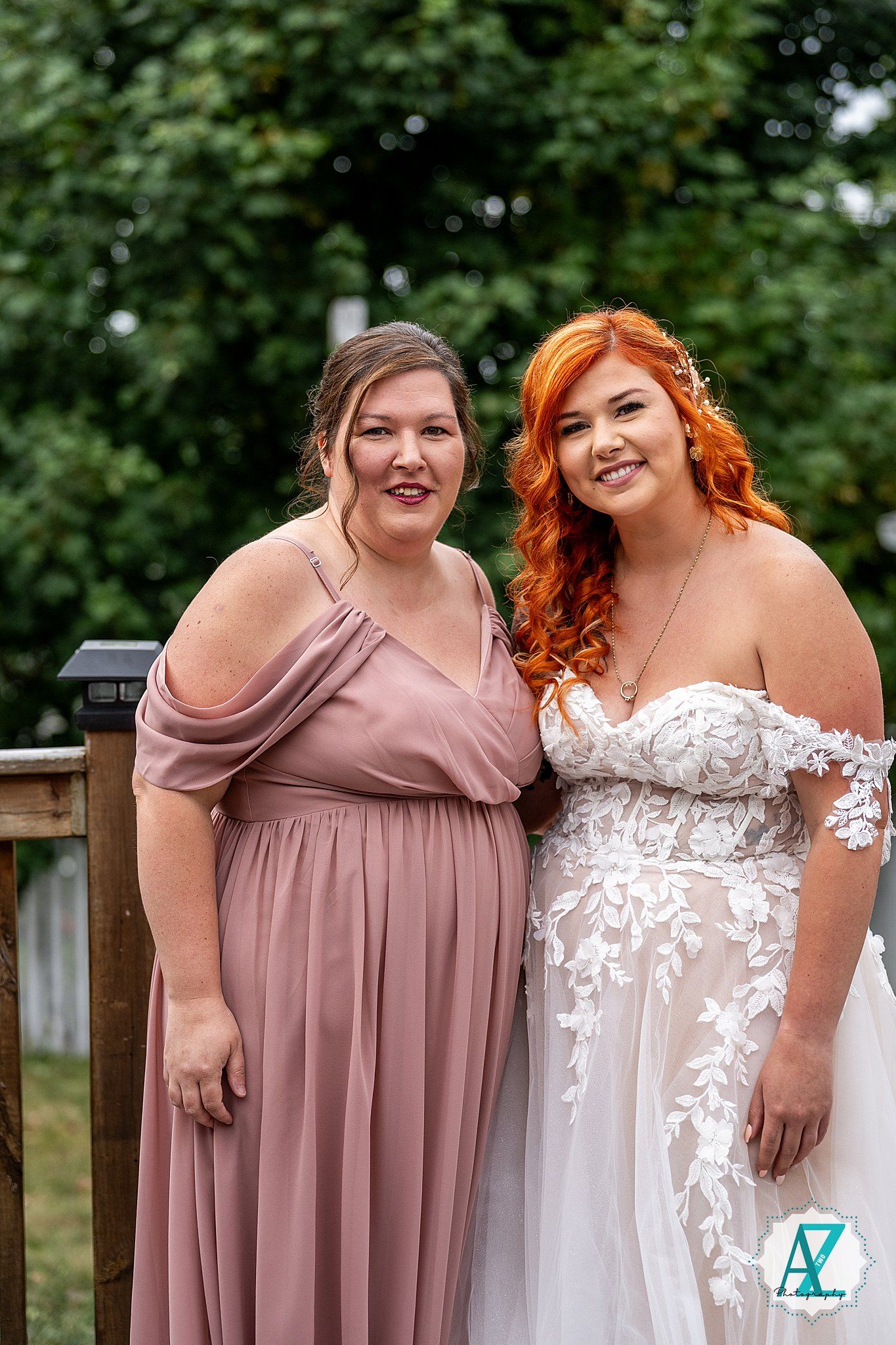Bridal party members share joyful moment in mauve and white gowns outdoors.