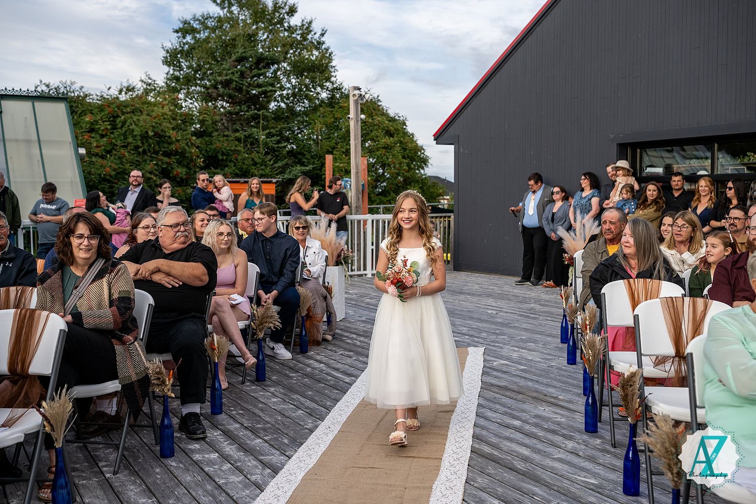 A group of wedding guests forms a line outside while holding sparklers during an evening celebration at an outdoor venue.