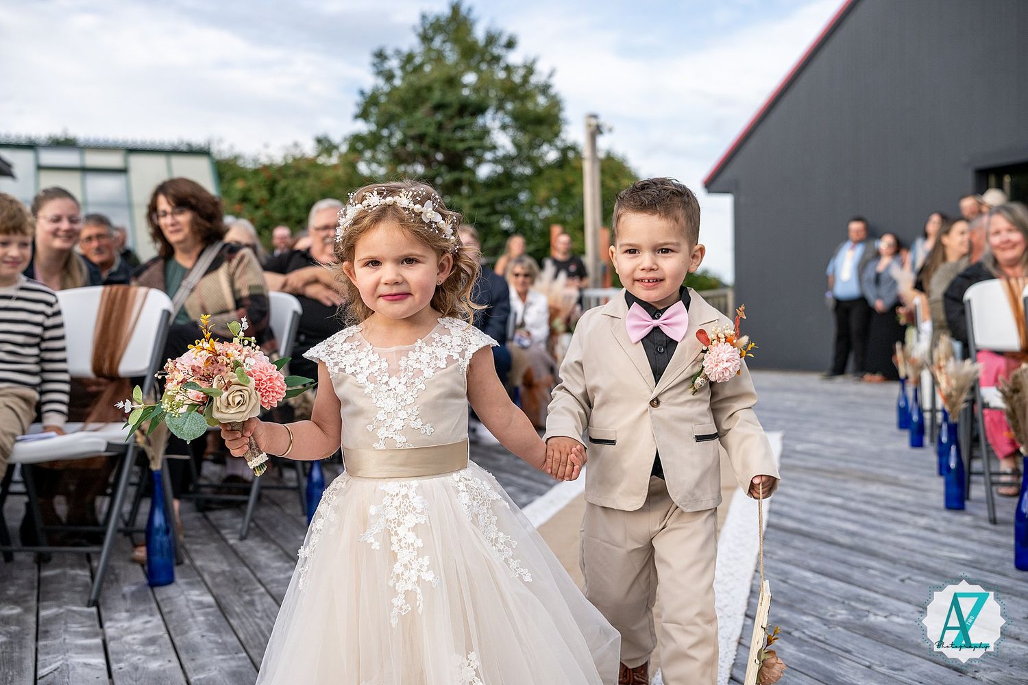 Wedding guests gather on wooden deck during outdoor celebration.
