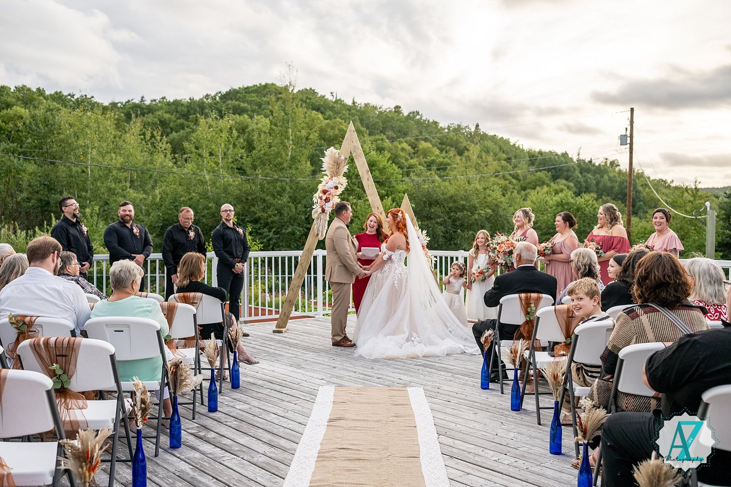 Outdoor wedding ceremony setup with white chairs and mountain backdrop.
