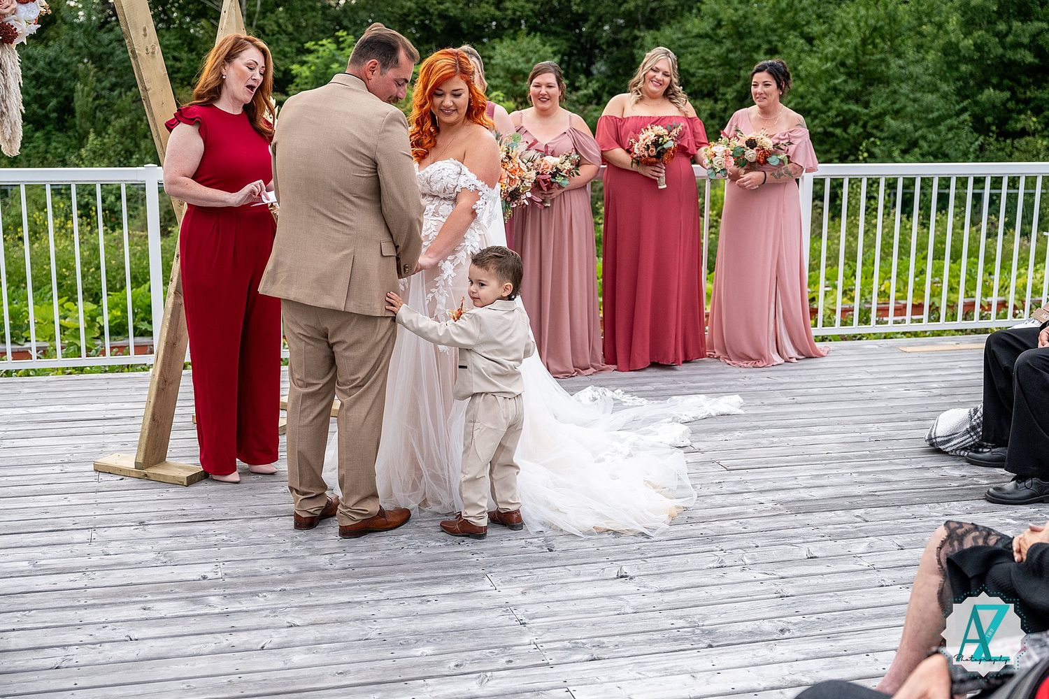 Wedding party stands on a wooden deck adorned with blue accents against a scenic mountain backdrop.