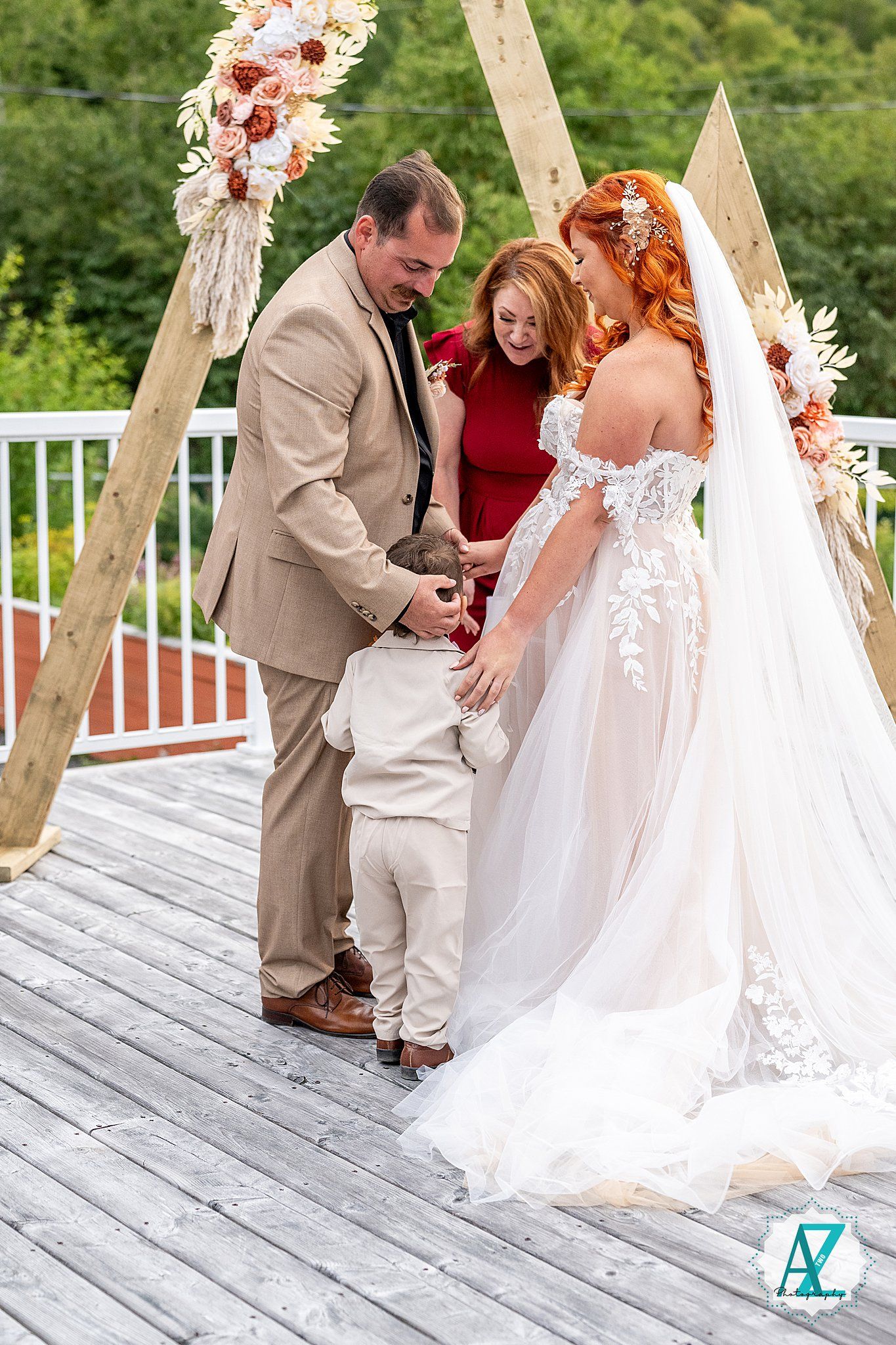 Intimate moment during wedding ceremony under floral arch on outdoor mountain deck.
