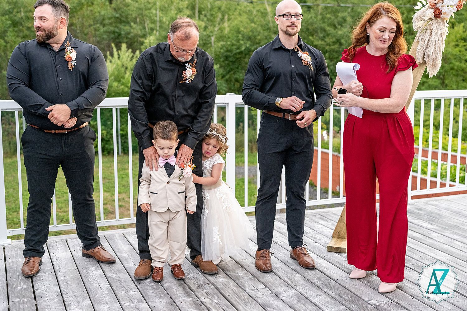 Row of formal shoes and feet lined up on wooden deck during wedding photo session.