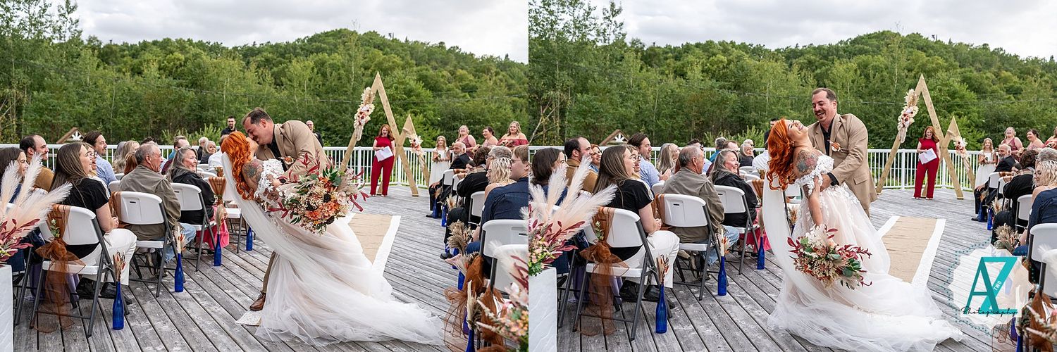 Outdoor wedding ceremony setup shows white chairs arranged in rows facing a rustic arch and backdrop overlooking green hills.
