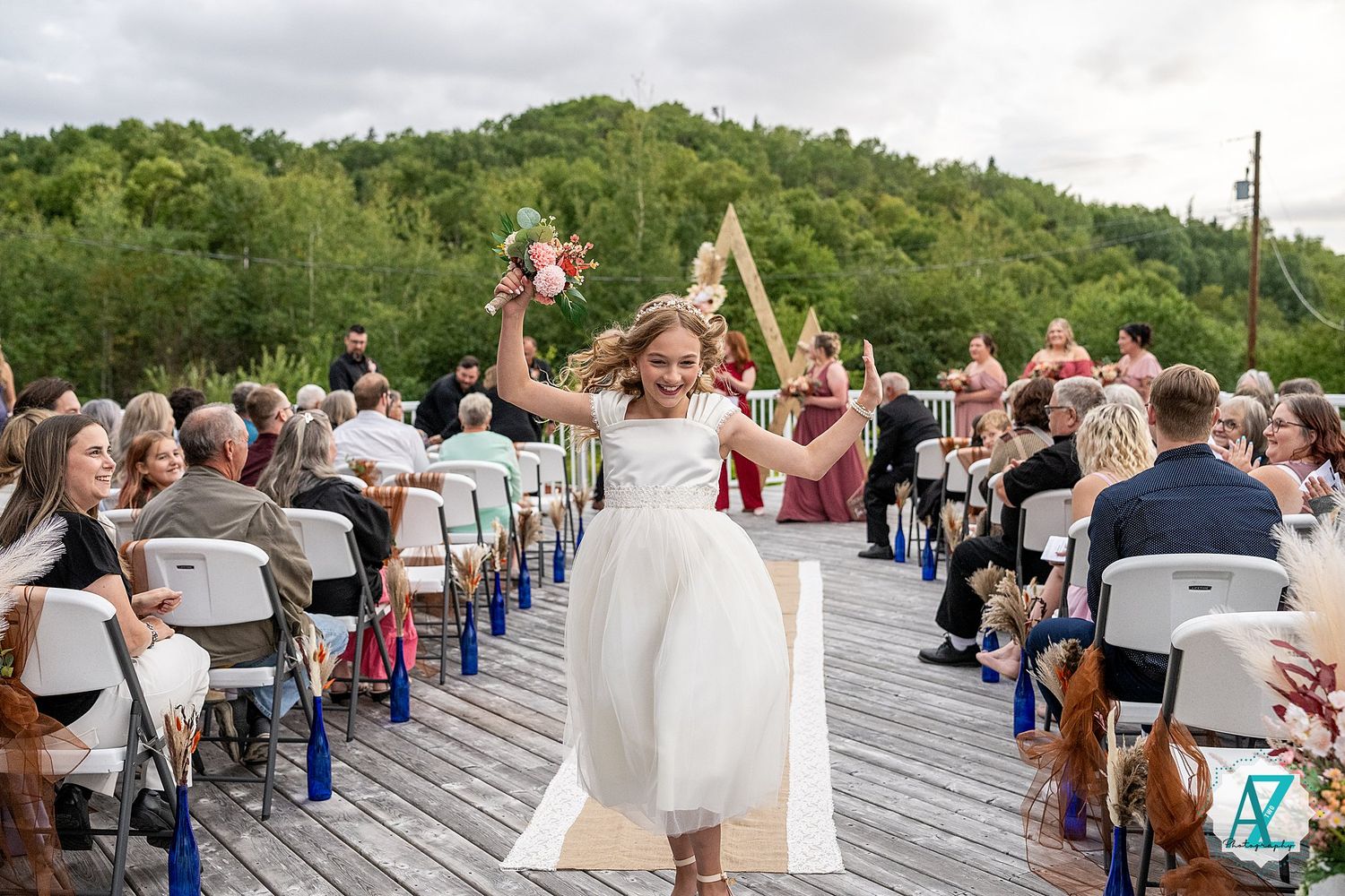 Wedding ceremony taking place on elevated wooden deck with scenic mountain backdrop.