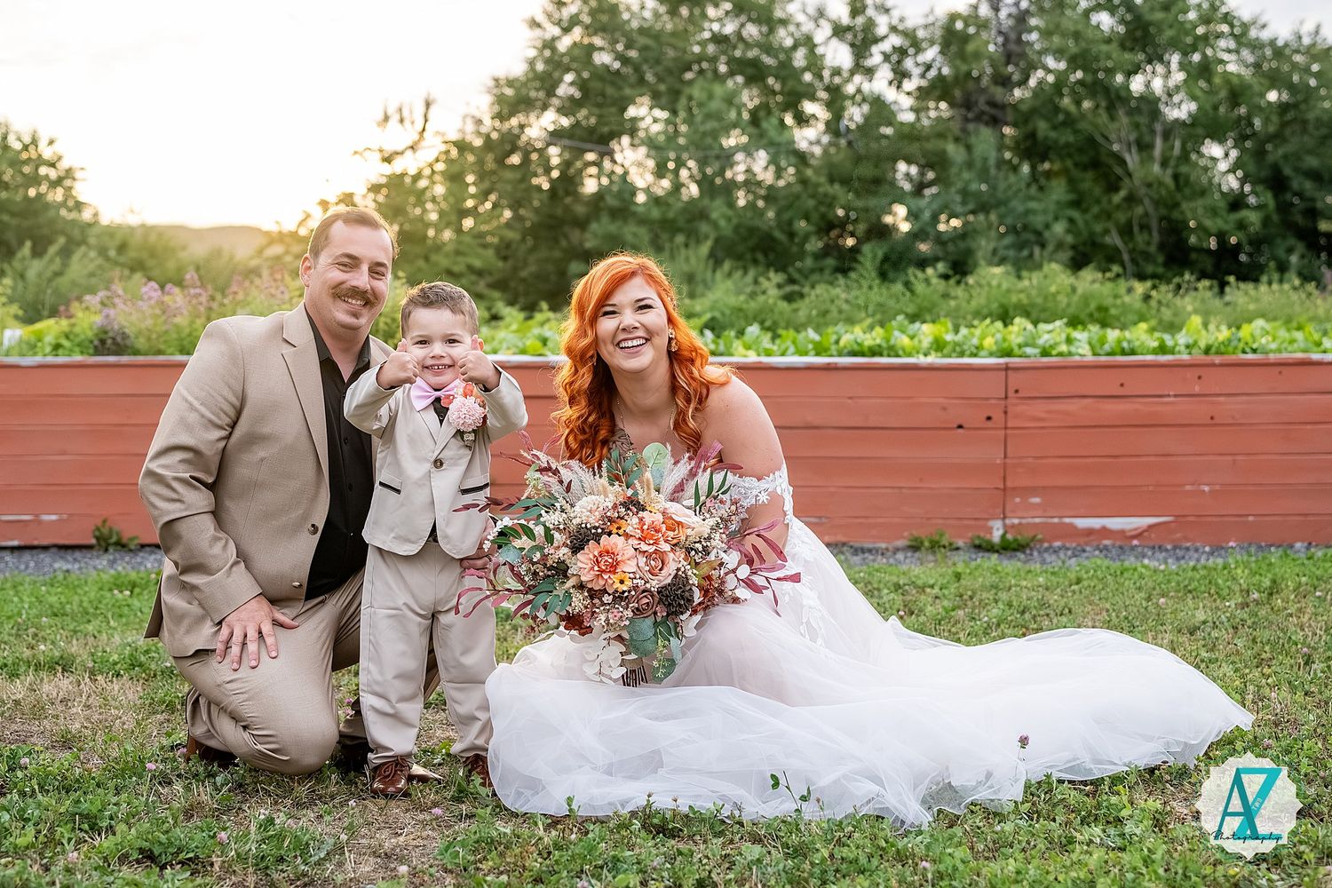 A couple sits with their dogs during a rustic outdoor wedding photo session.