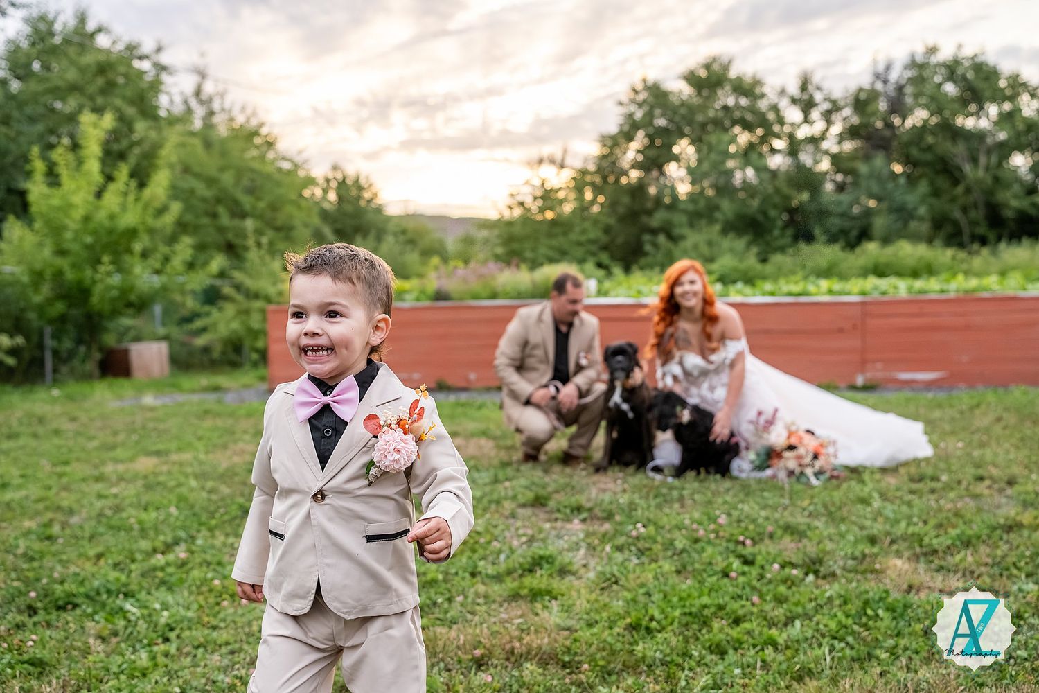 Wedding couple and family pose together on grassy field at outdoor garden ceremony.