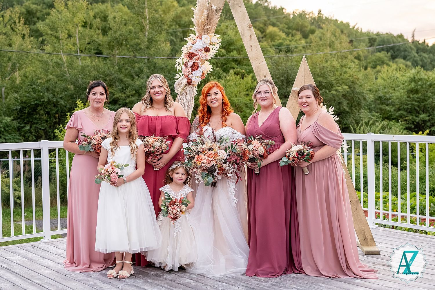 Bridal party lineup with pink and burgundy dresses against mountain backdrop.