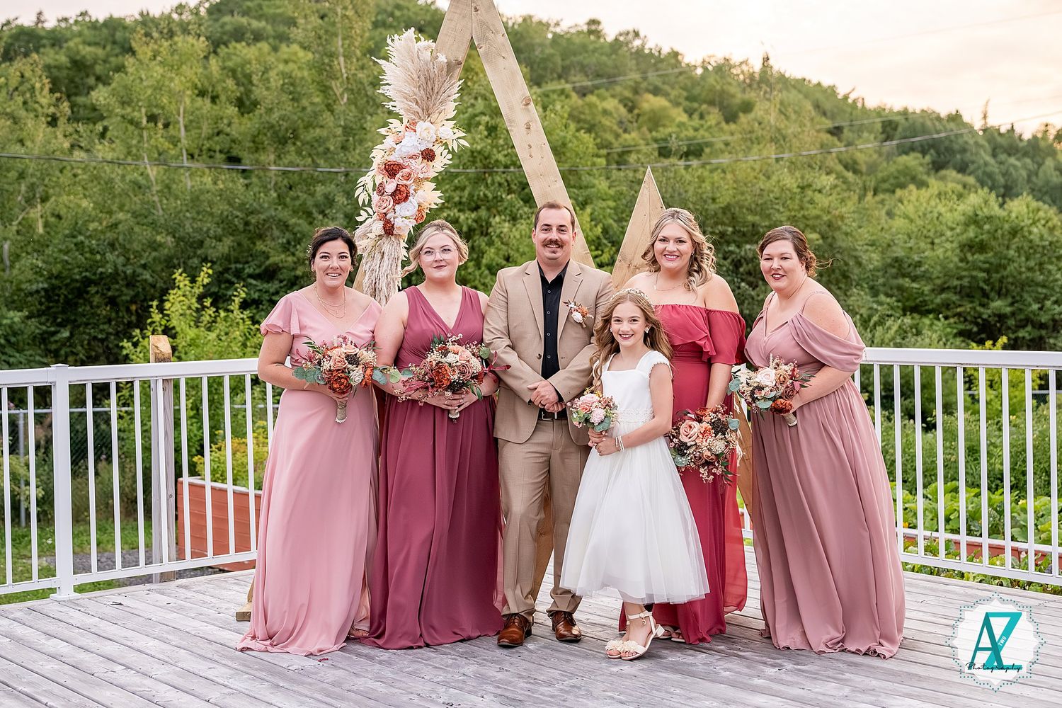 Wedding group photo with bridesmaids in pink dresses and flower girls in white.