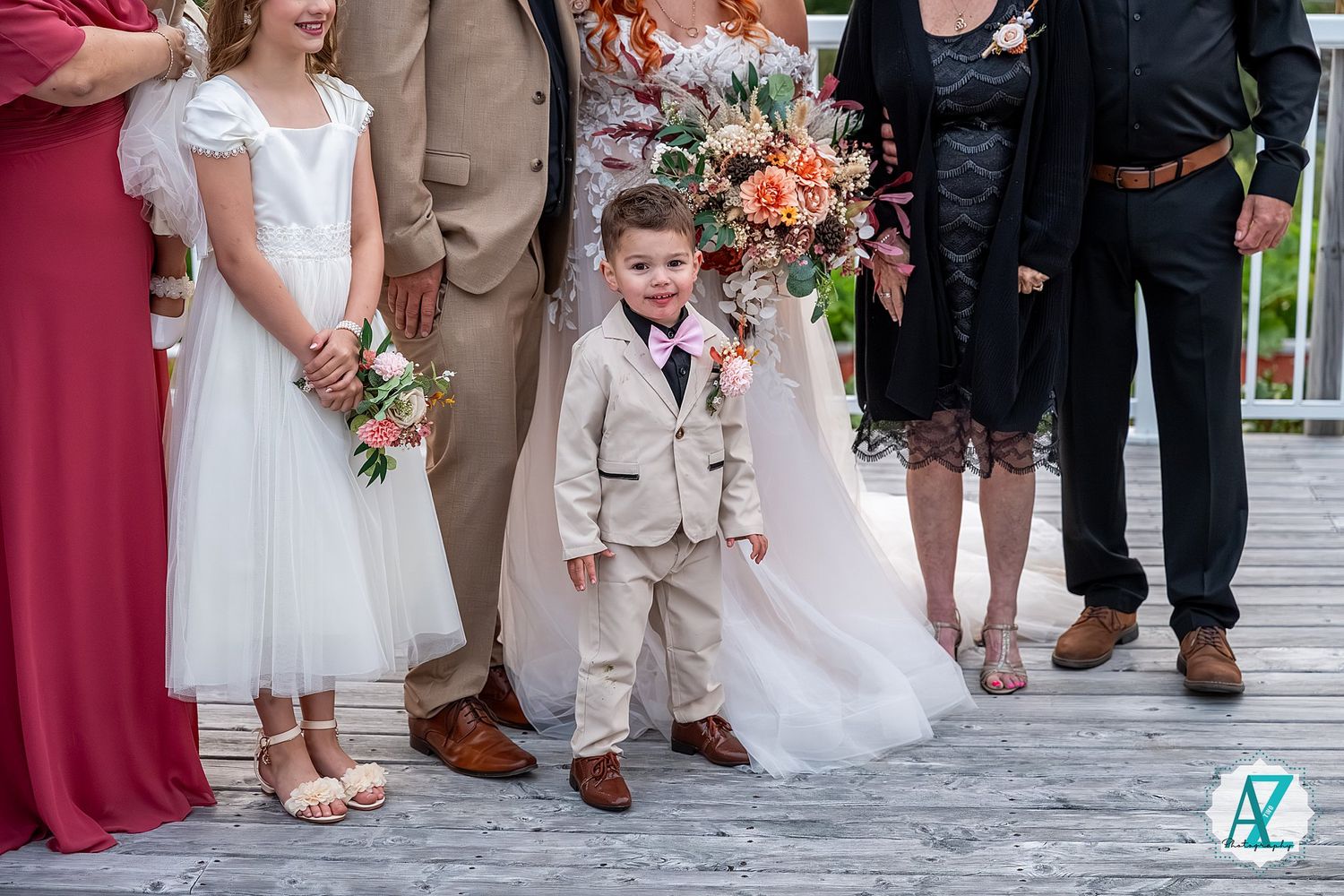 Wedding party members posing together in formal attire during outdoor celebrations.