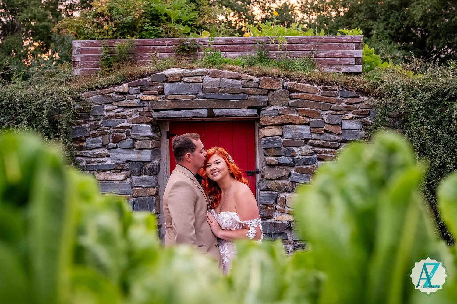 A romantic photo session in front of a rustic stone wall with lush green foliage.