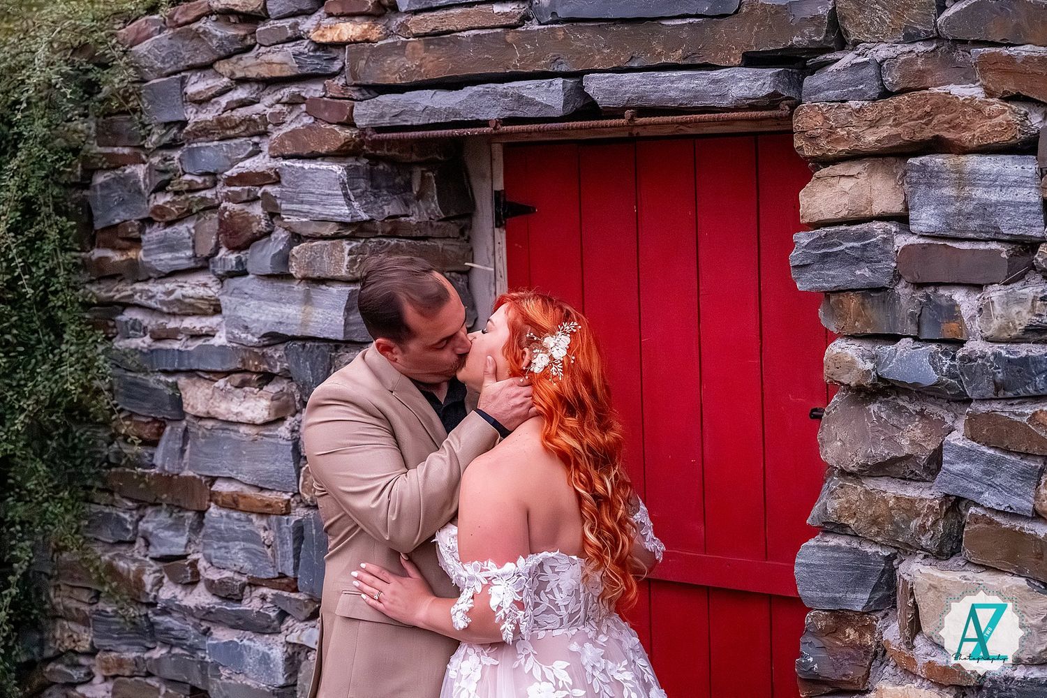 Romantic stone wall backdrop with bright red door frames couple's intimate wedding moment.