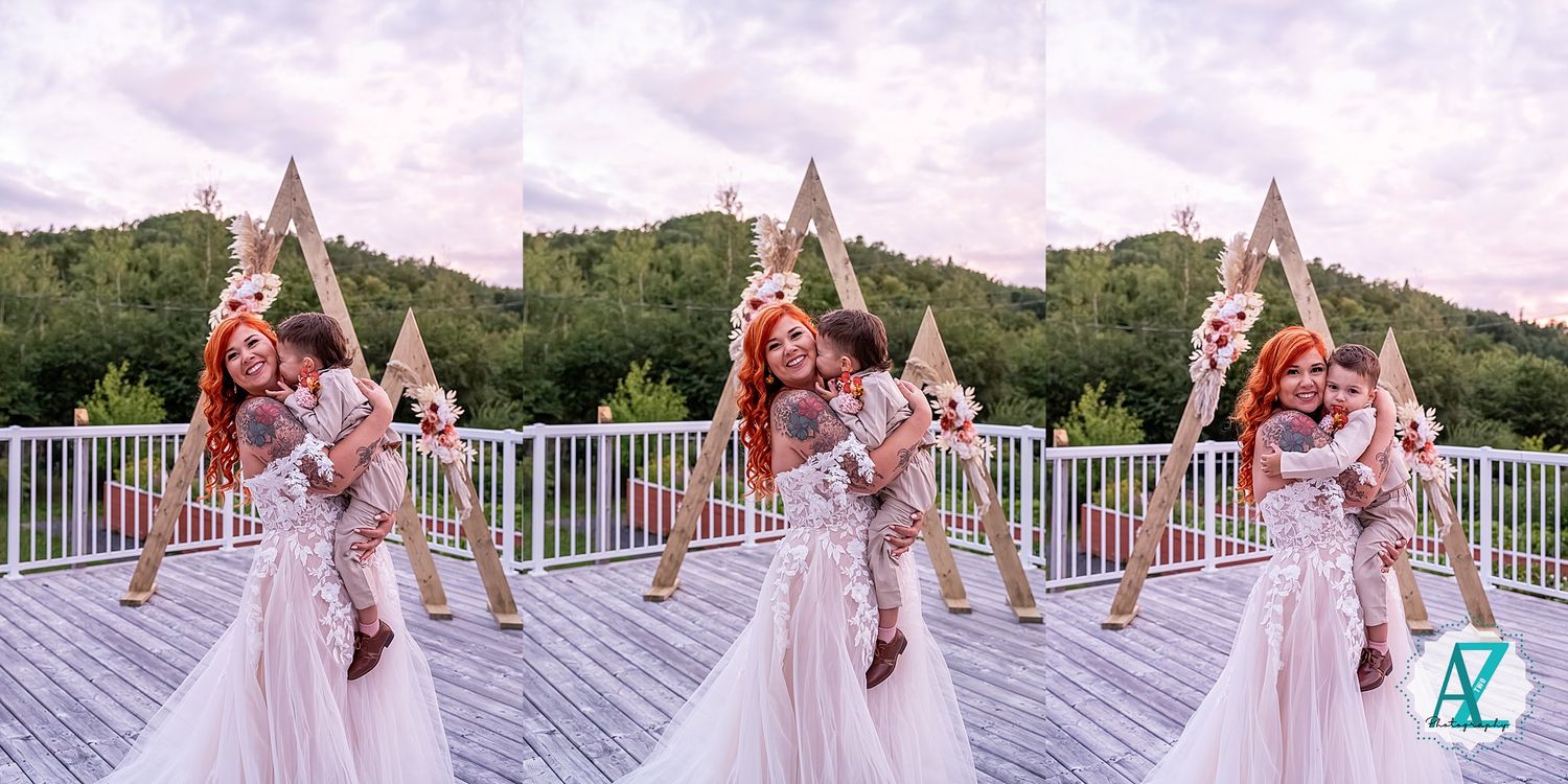 Wedding ceremony setup on a deck with floral arch and pink accents against a mountain backdrop.