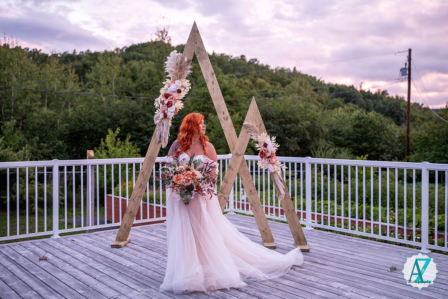 Ornate wedding arch setup on an outdoor deck with mountain views and floral decorations.
