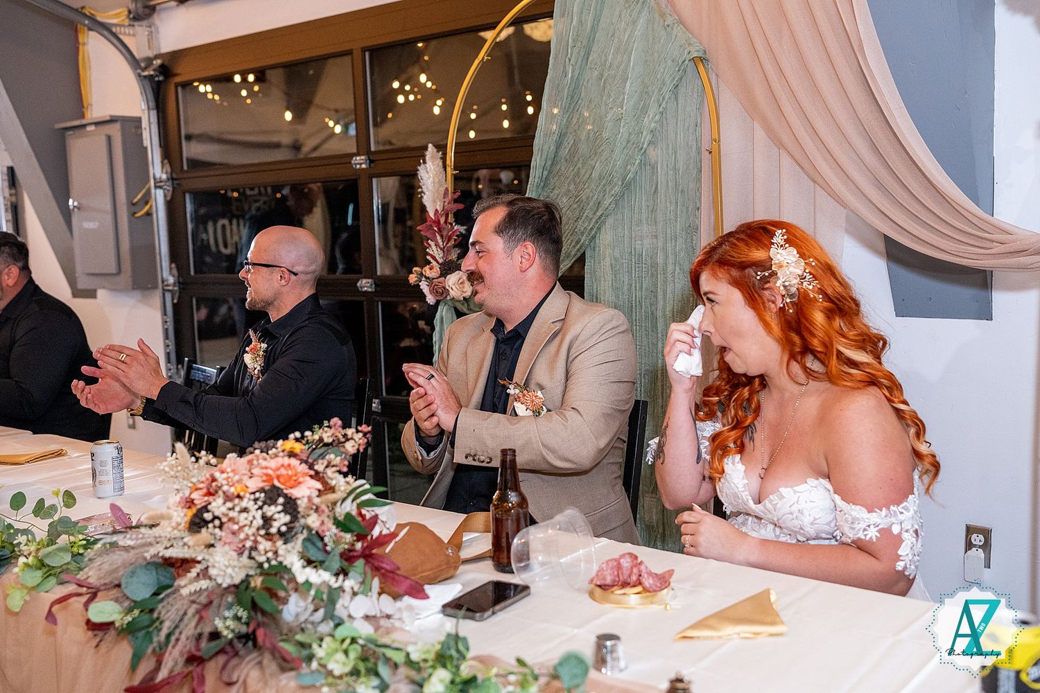 Wedding guests share laughter and conversation around an elegantly decorated table with pink draping and flowers.