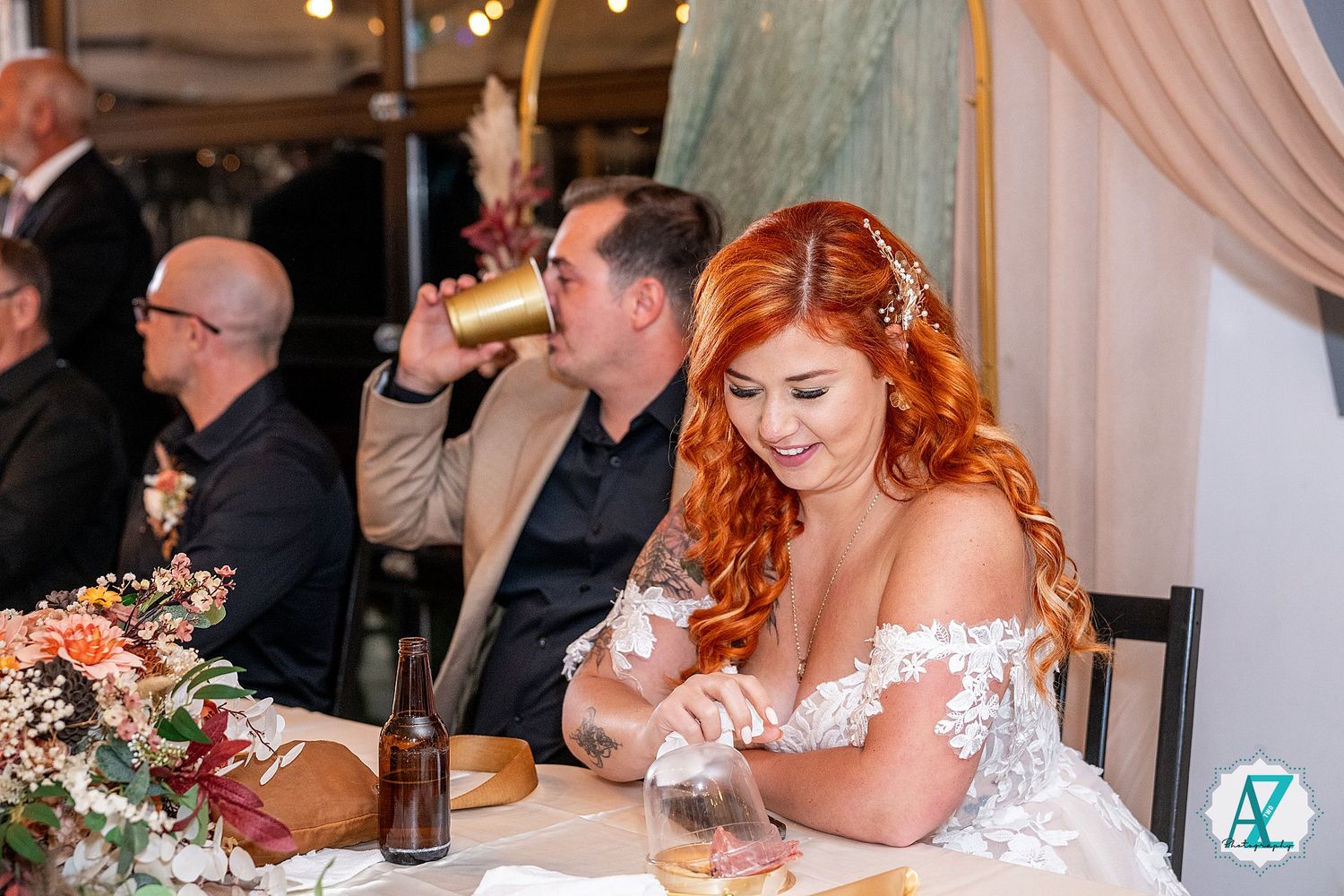 A couple laughs and smiles during their wedding reception dinner at a rustic venue with wood panel backdrop.