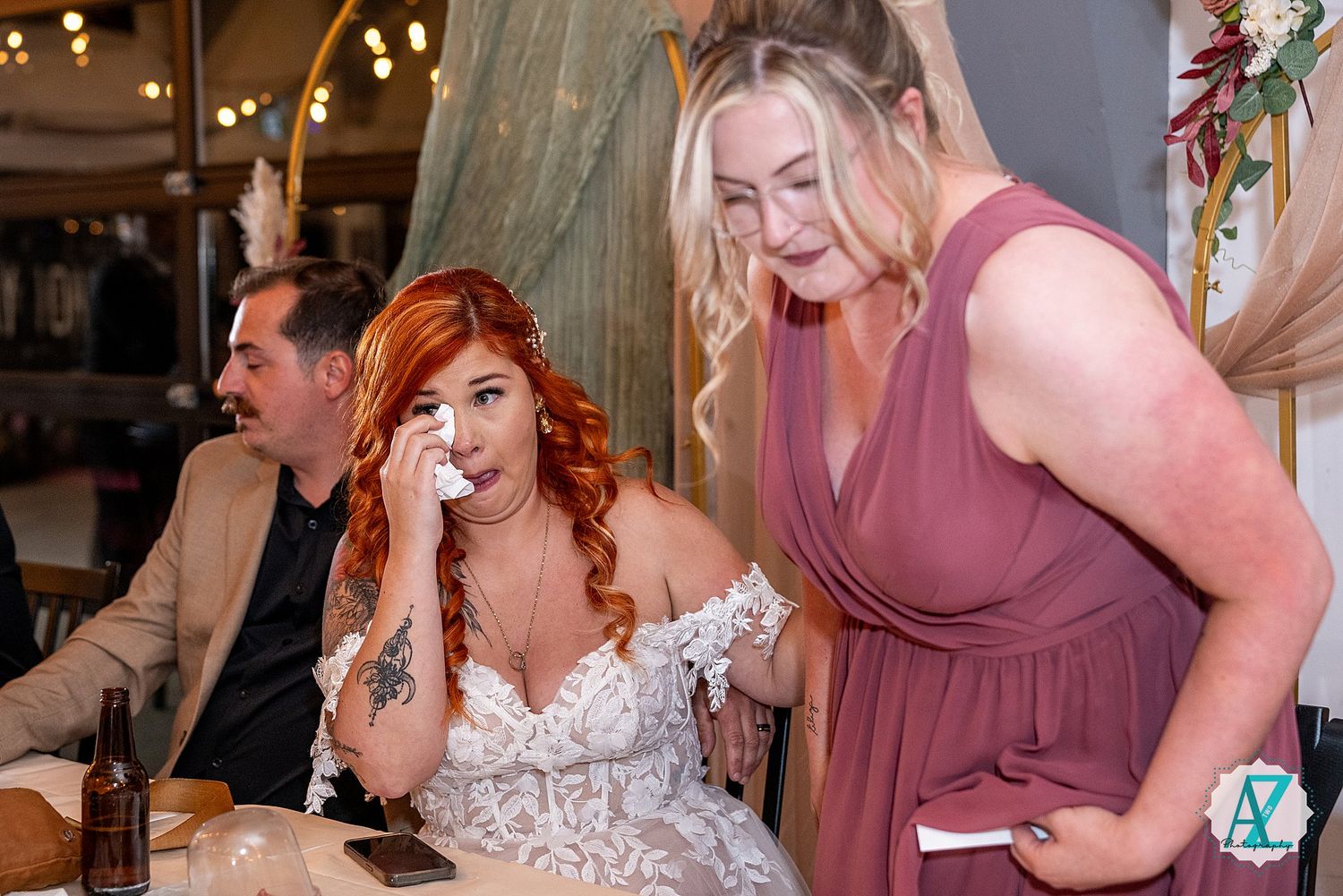 Wedding party members sharing emotional moments during indoor reception celebrations.