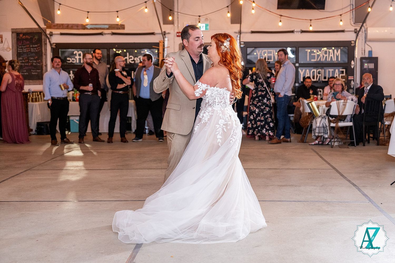 Bride in white wedding dress twirls on dance floor during reception while guests watch from tables.