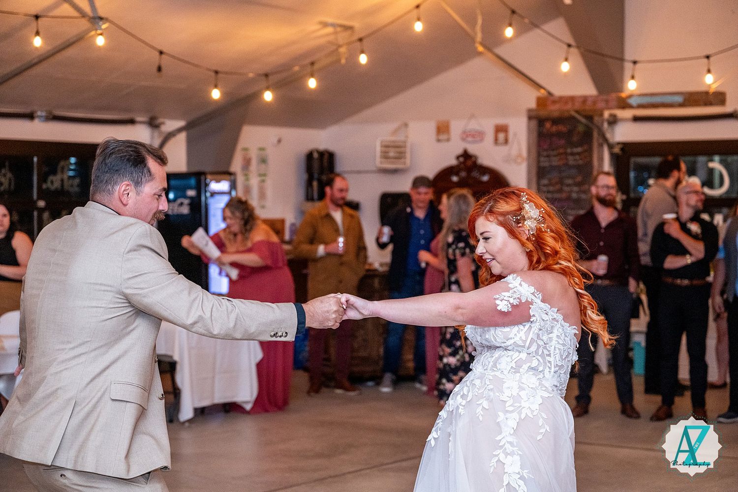 Wedding party breaks into joyful dance moves during a reception in a beautifully lit indoor venue.