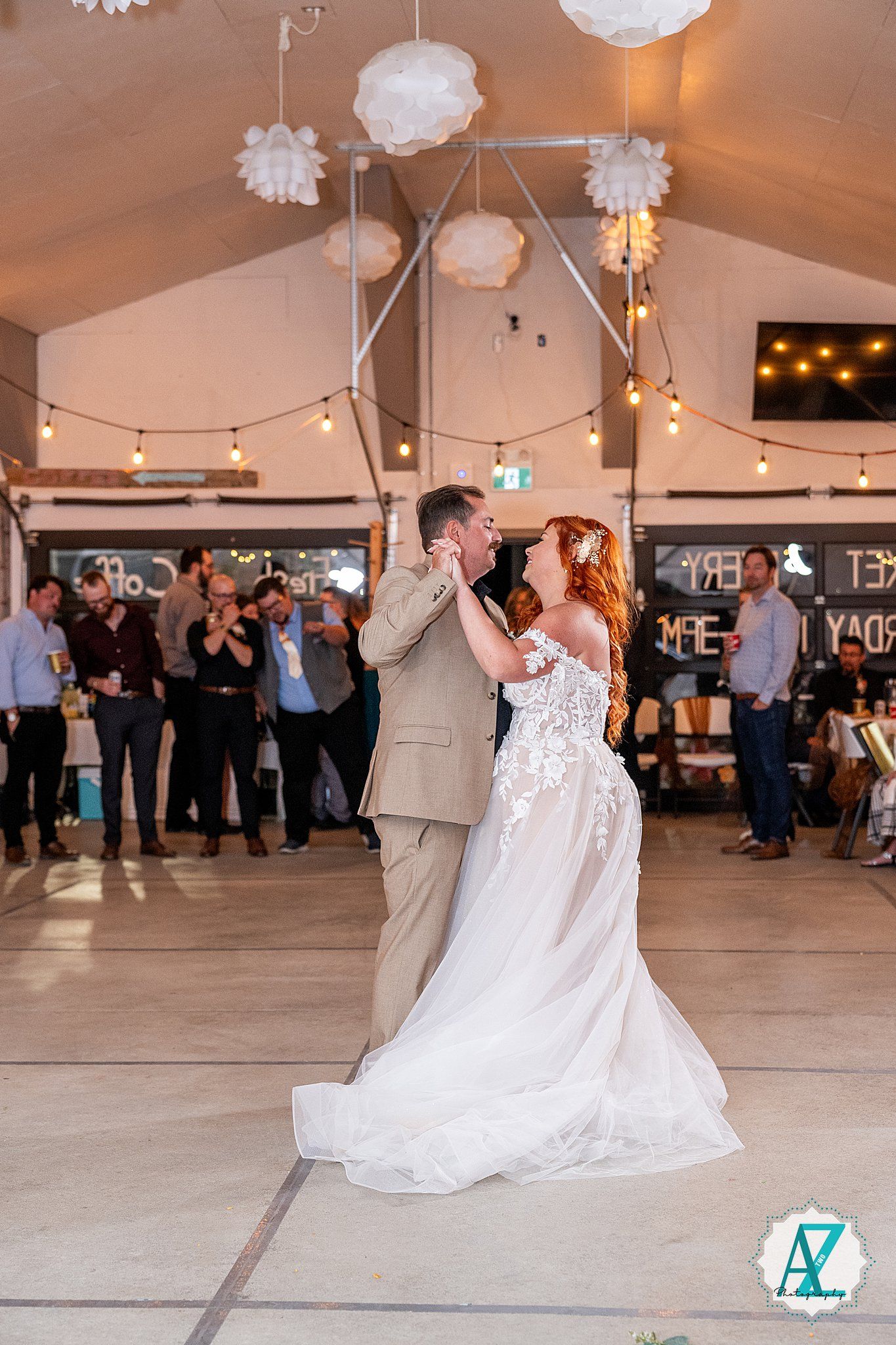 Wedding couple performs romantic dance sequence at reception venue decorated with hanging paper lanterns and string lights.