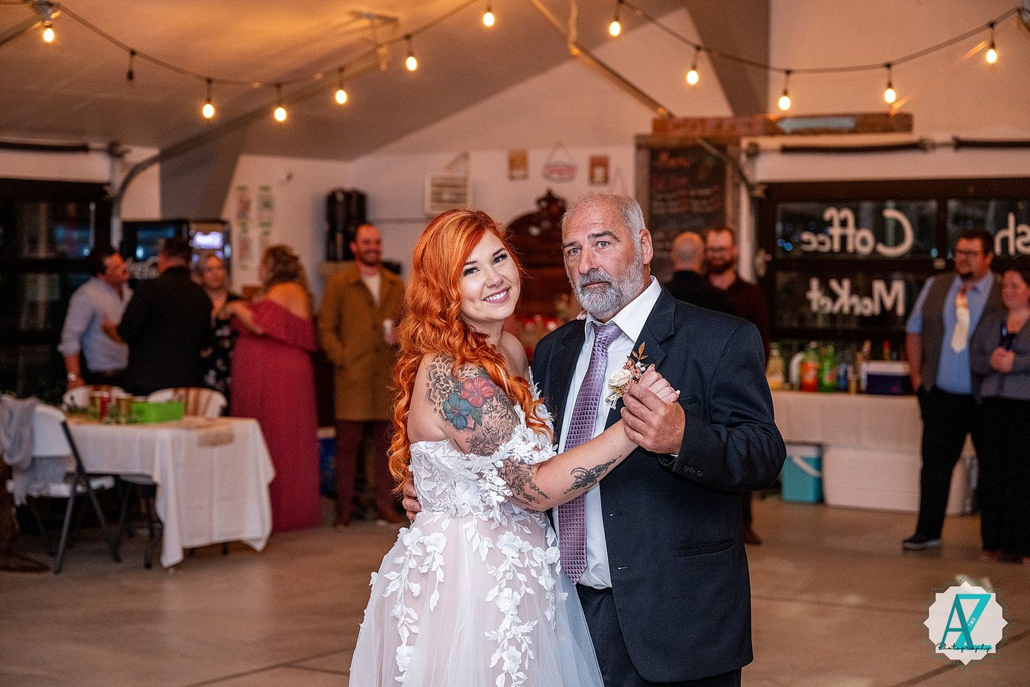 Couples dancing at an indoor event space with romantic string lighting and exposed brick walls.