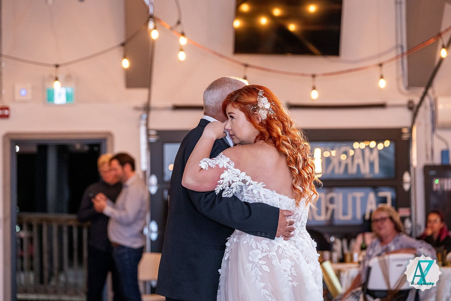 A joyful celebration captured indoors with string lights and party guests in formal attire.